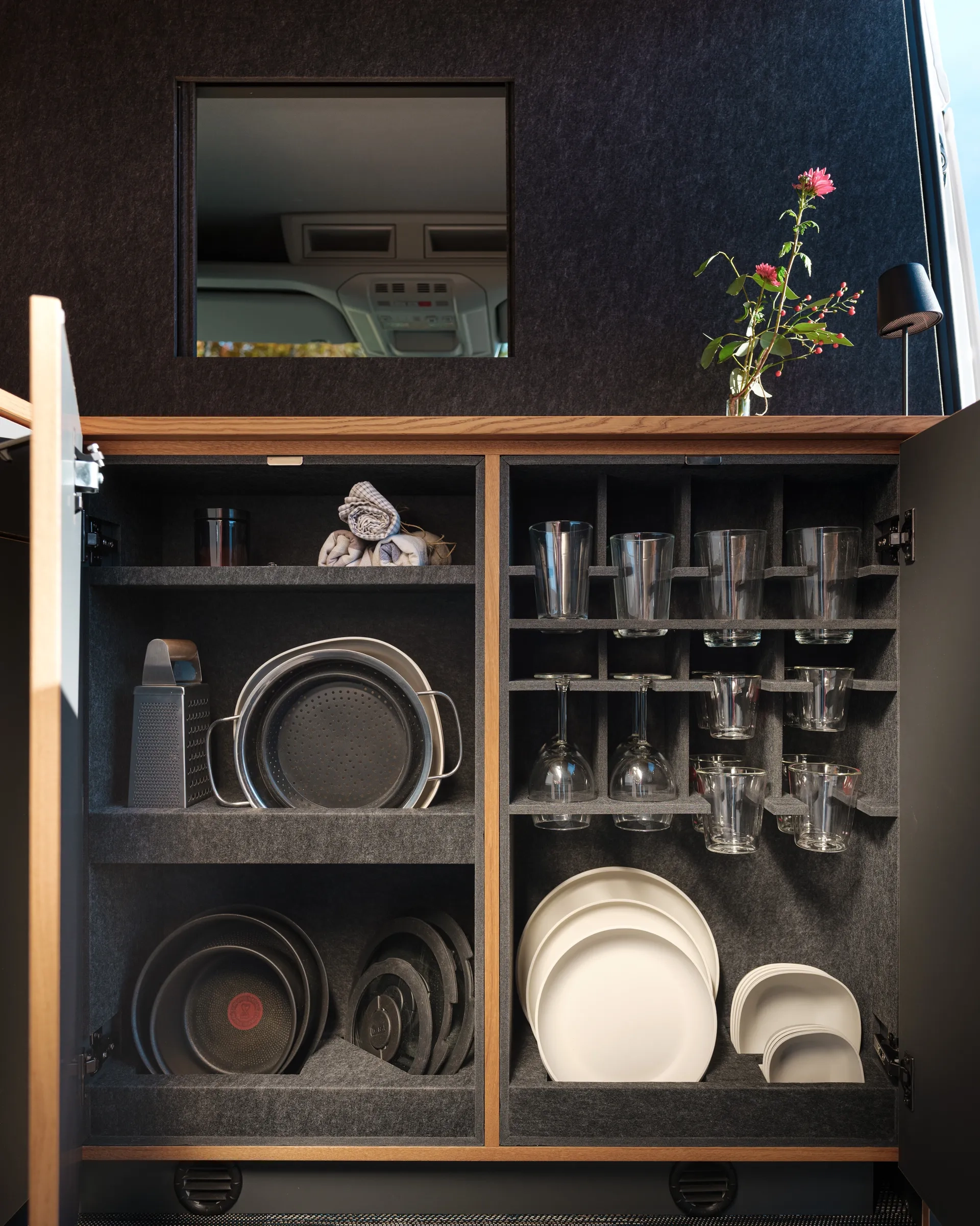 Vollausgerüstete Küche im Camper Van Patgific von Cocoon Vans. Die Möbel sind mit robustem Filz ausgestattet, die Halterungen für Gläser und Teller sind aus dem Filz geschnitten, so das alles an seinem Platz bleibt.