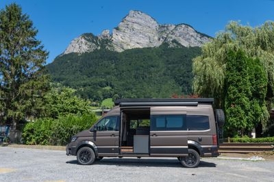 Blick seitlich in den Camper Van durch die geöffnete Seitentüre. Die geöffnete Türe gibt den Blick auf individuell geschreinerte Möbel im Camper Van von Cocoon Vans frei
